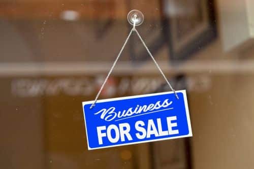 Blue sign hanging at the glass door of a shop saying: 