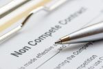 Legal concept : Blue ballpoint pen on a non compete contract. Concept for Ohio non-compete agreement: Should I litigate or negotiate?